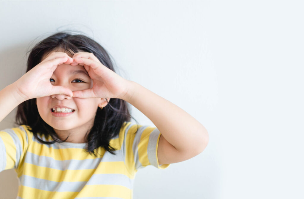 Young girl creating heart around eye to signify healthy eyes and sight