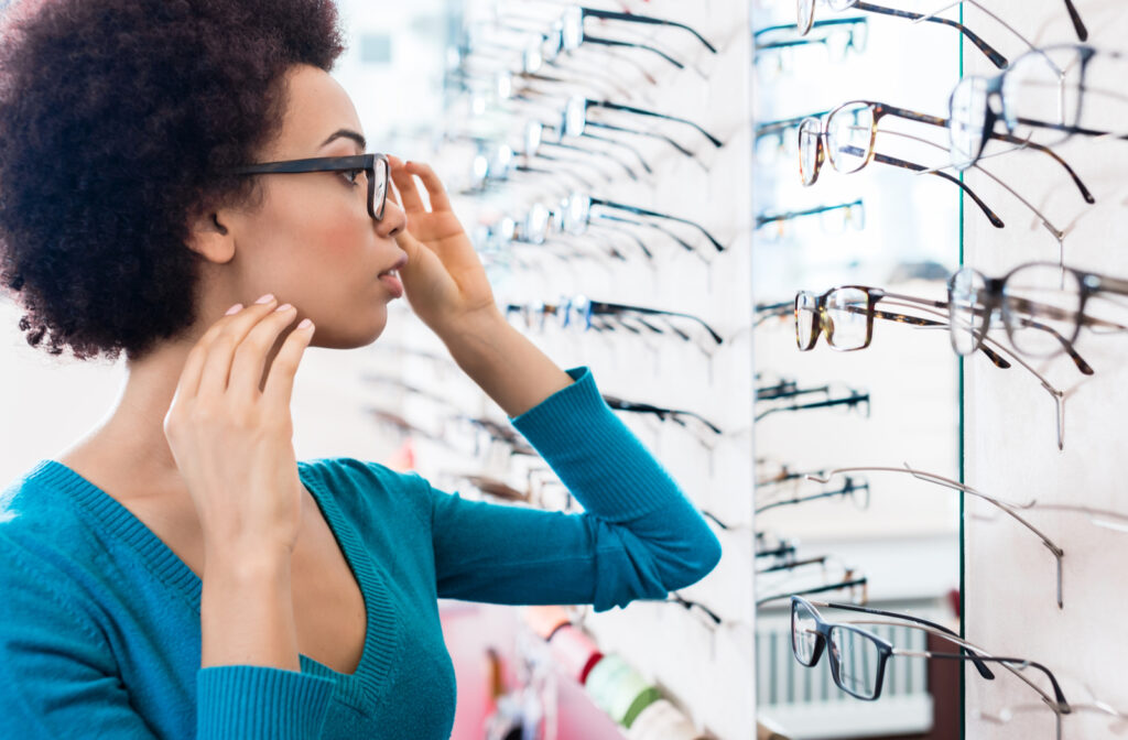 Women looking at herself in mirror while searching for glasses that suit her face the best
