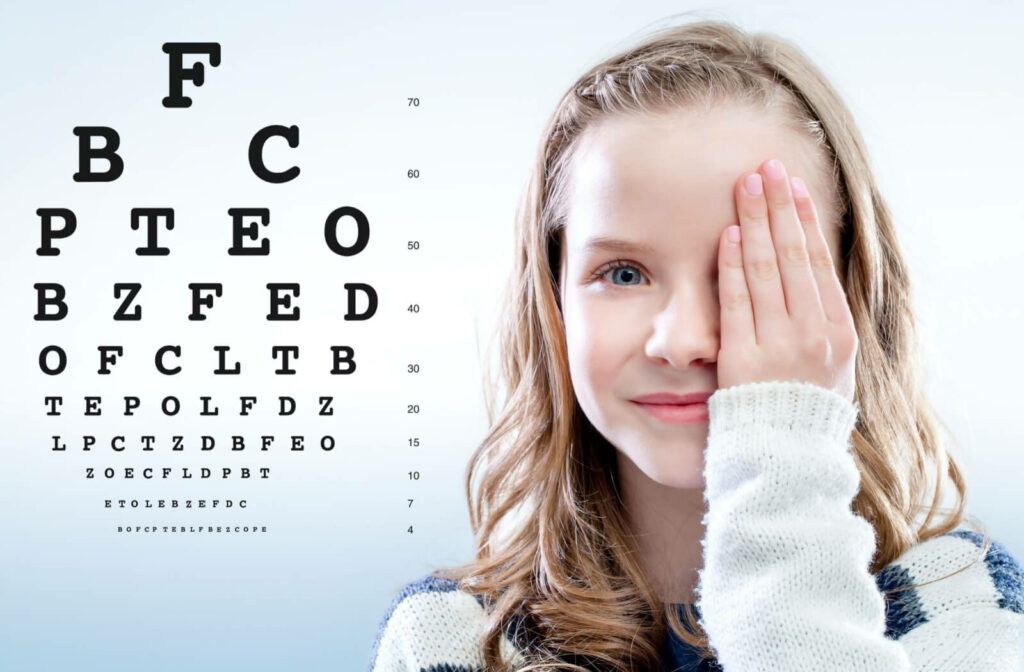 A young girl with her left hand covering her left eye while performing a Snellen vision test.