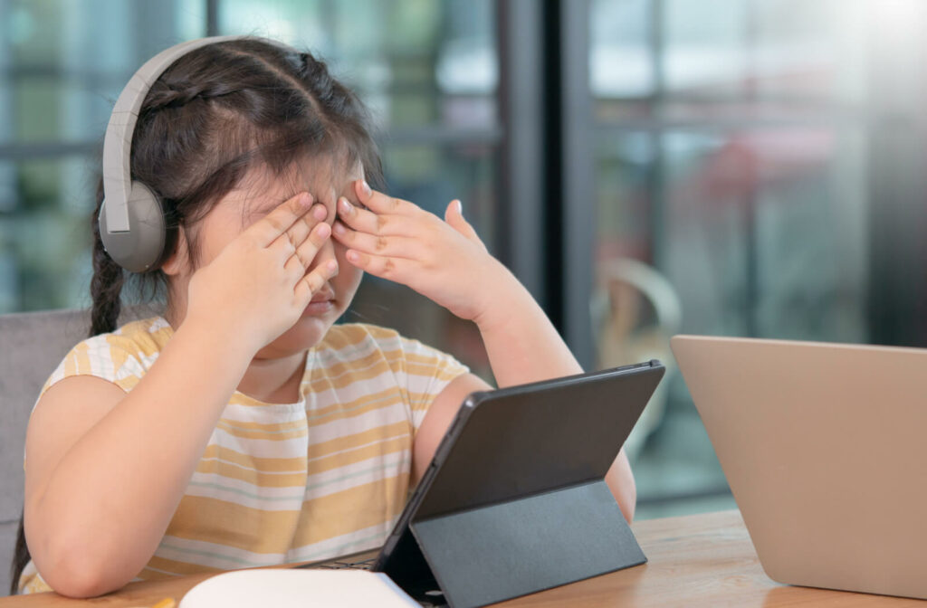 A female child is covering her tired eyes after using her tablet pc for a long period of time.