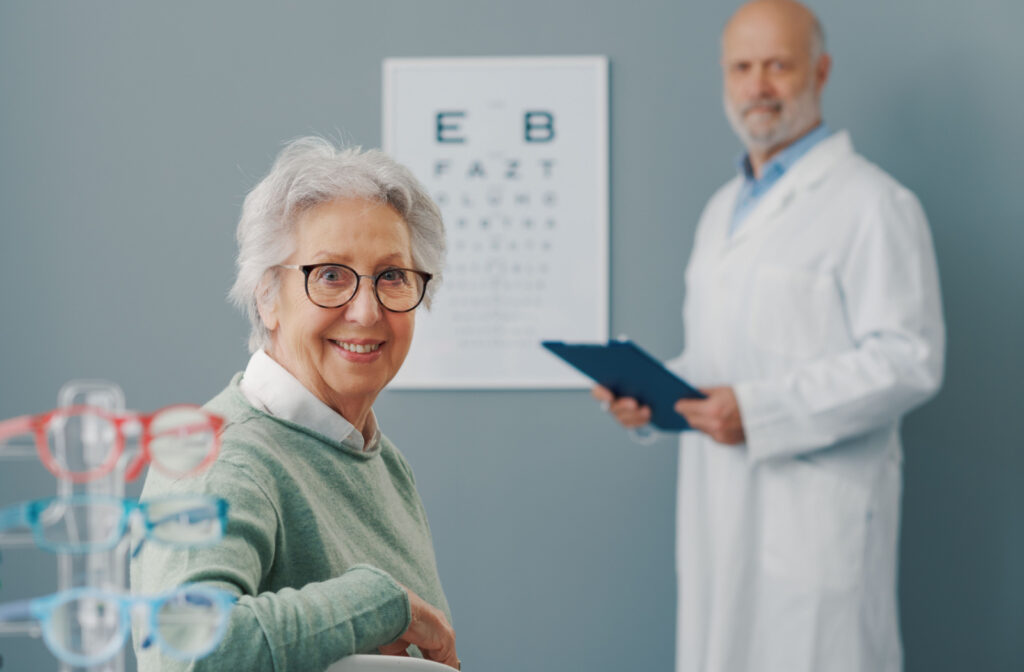 A senior woman smiling at the camera while having an eye exam with an optometrist.