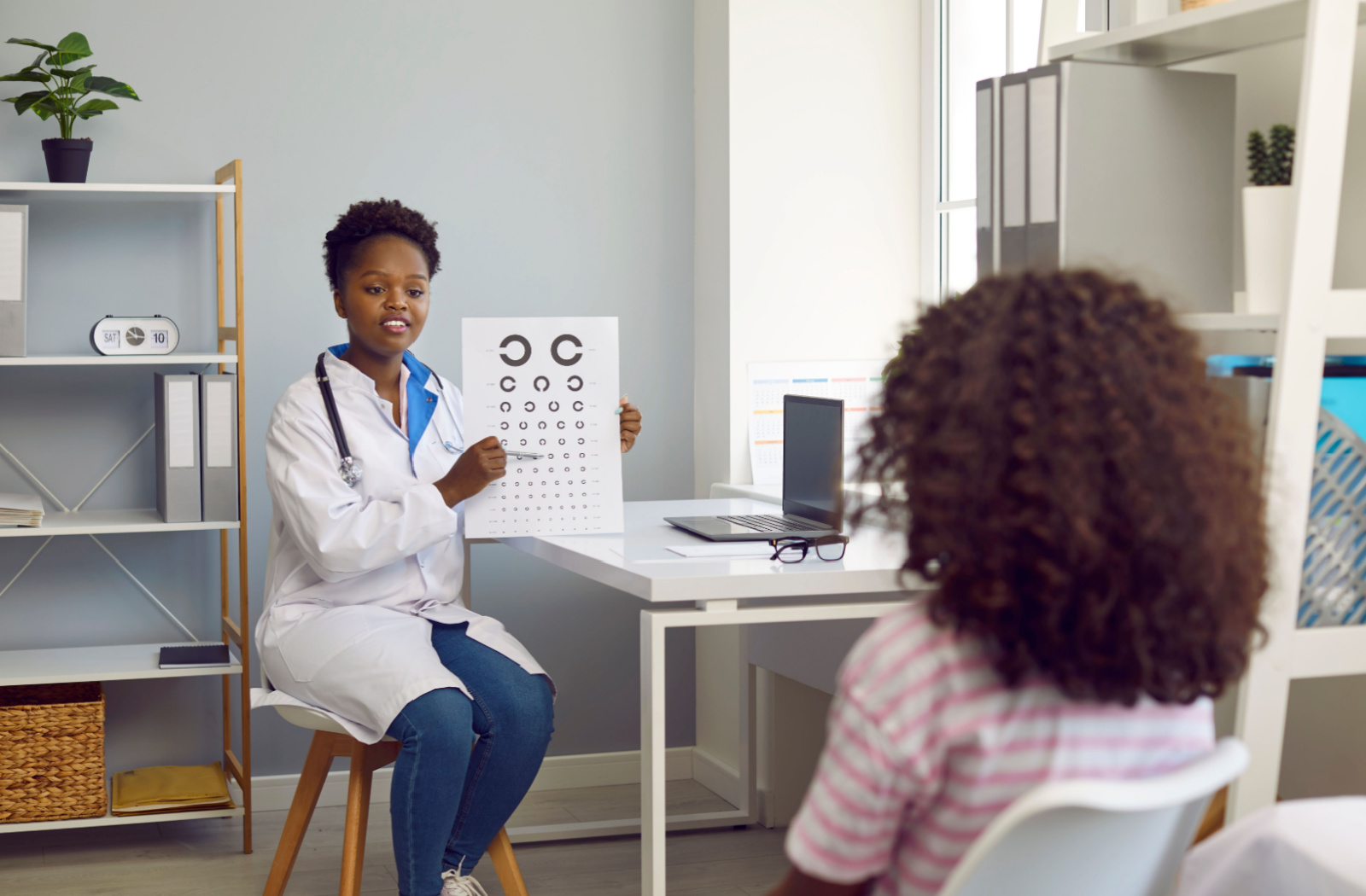 An eye doctor tests a young patient's eyesight with the Landolt C eye chart.