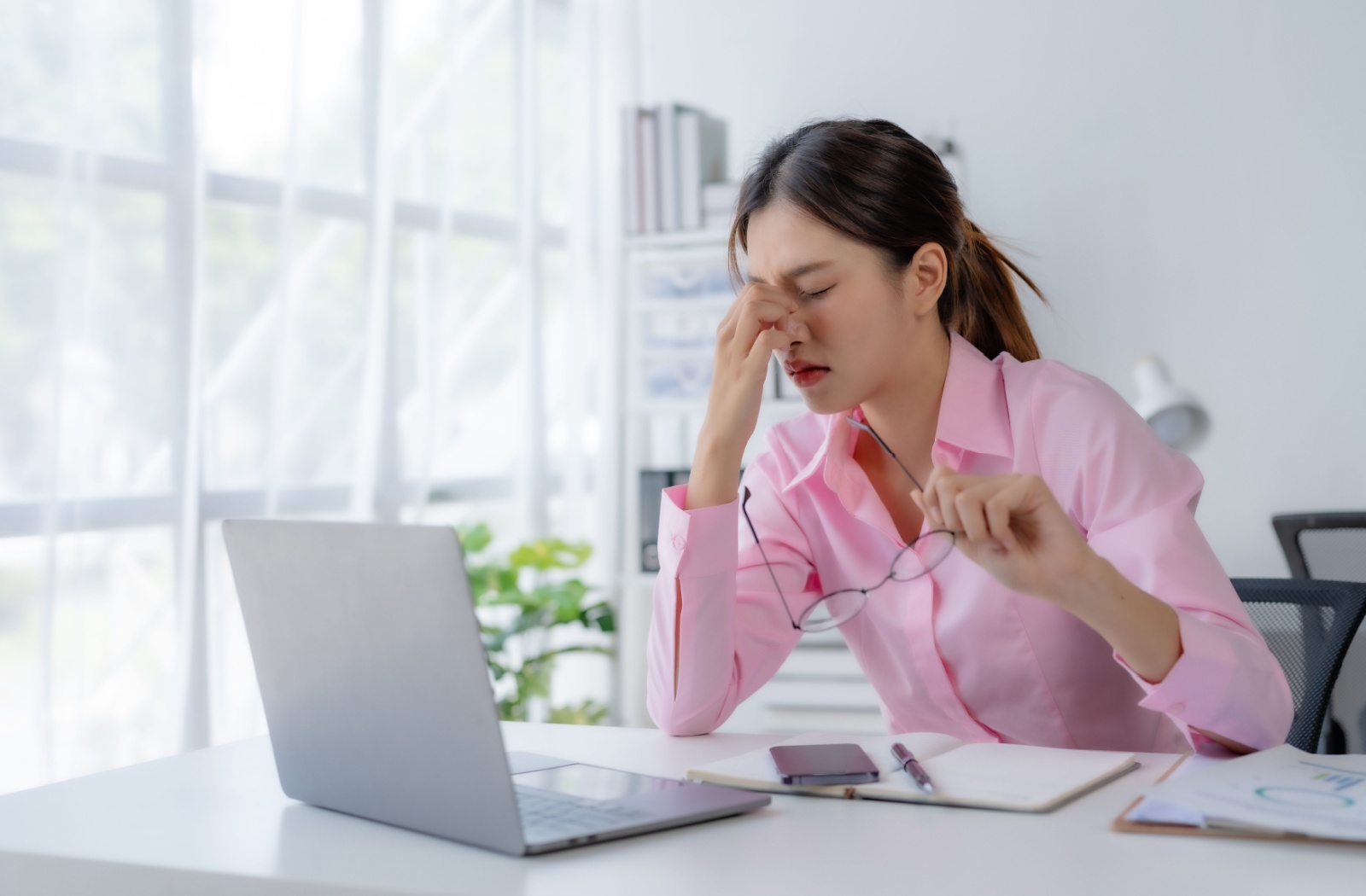 A woman rubbing her eyes after using her laptop for an extended period.