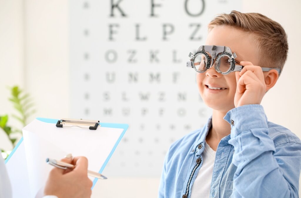 A young boy smiling during his vision assessment at his routine eye exam.