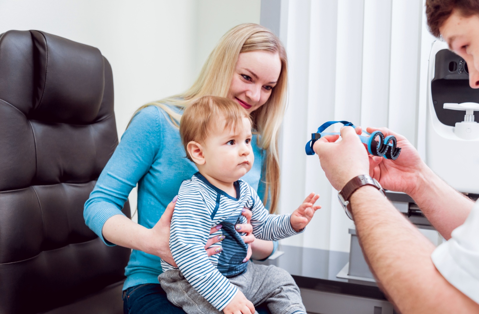 A baby sitting on their mother's lap at their first eye exam appointment.