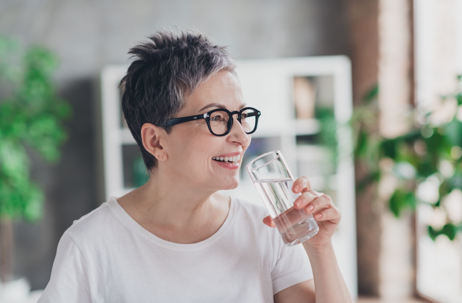 An older person drinking a glass of water to help stay hydrated.