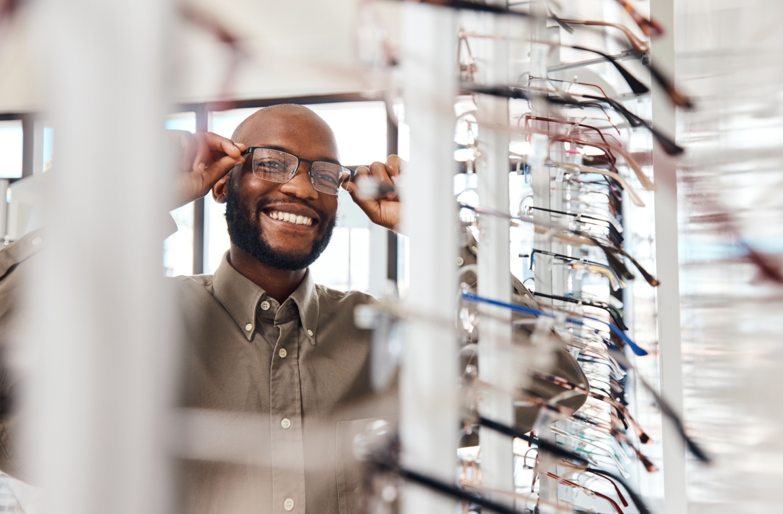 Smiling person trying on prescription glasses in an optometry store showcasing frame options for long-lasting eyewear