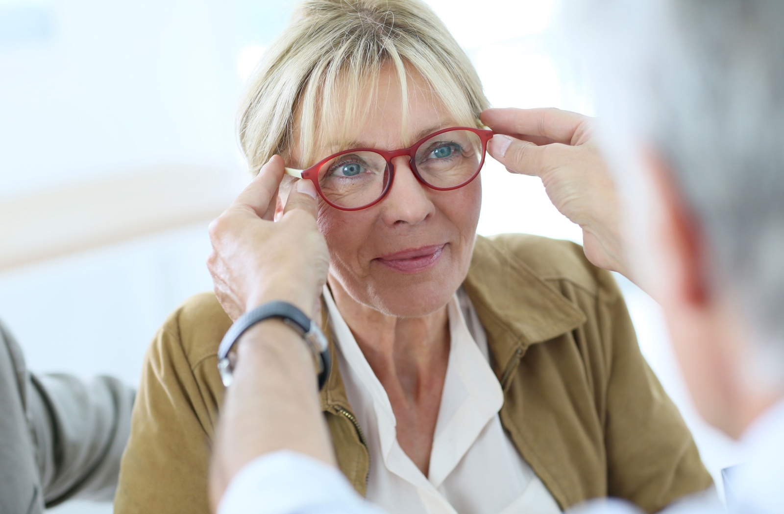 Woman being fitted with red progressive glasses at optician.