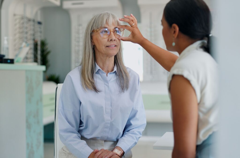 An optometrist adjusts a patient's glasses during a vision check inside an eye care clinic.