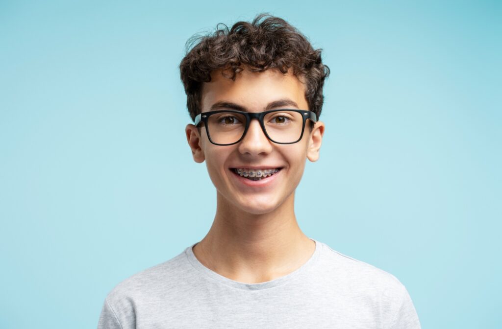 A preteen child wearing glasses standing infront of a light blue background