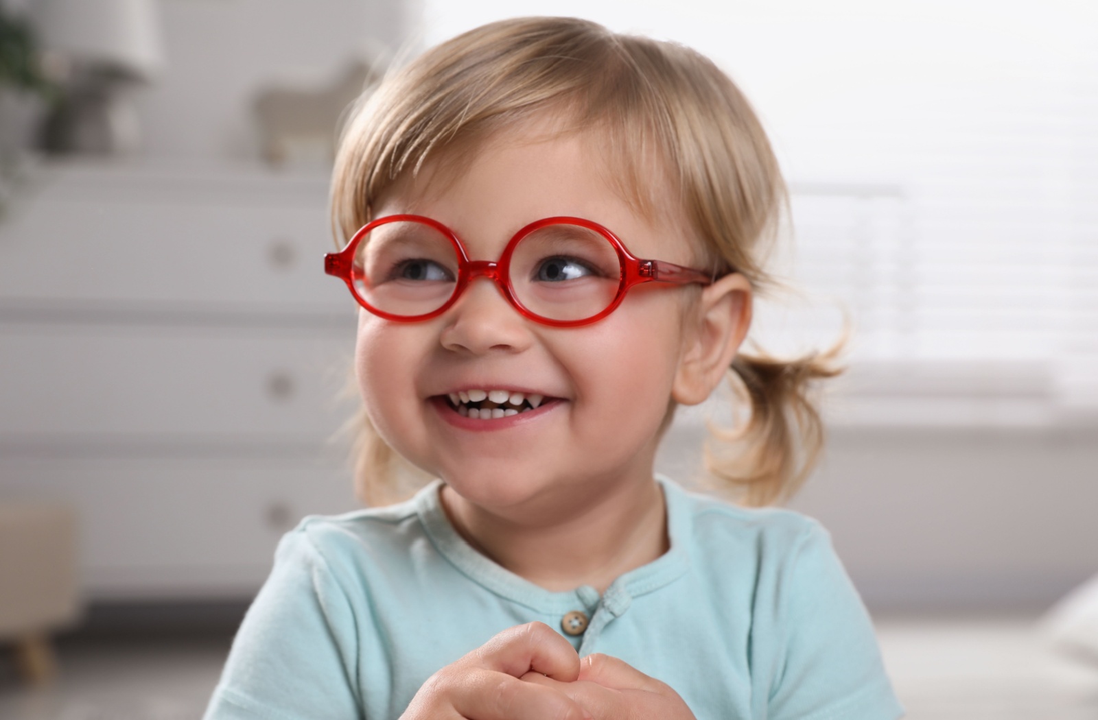 A young child cheerfully wears their red, myopia control eyeglasses.