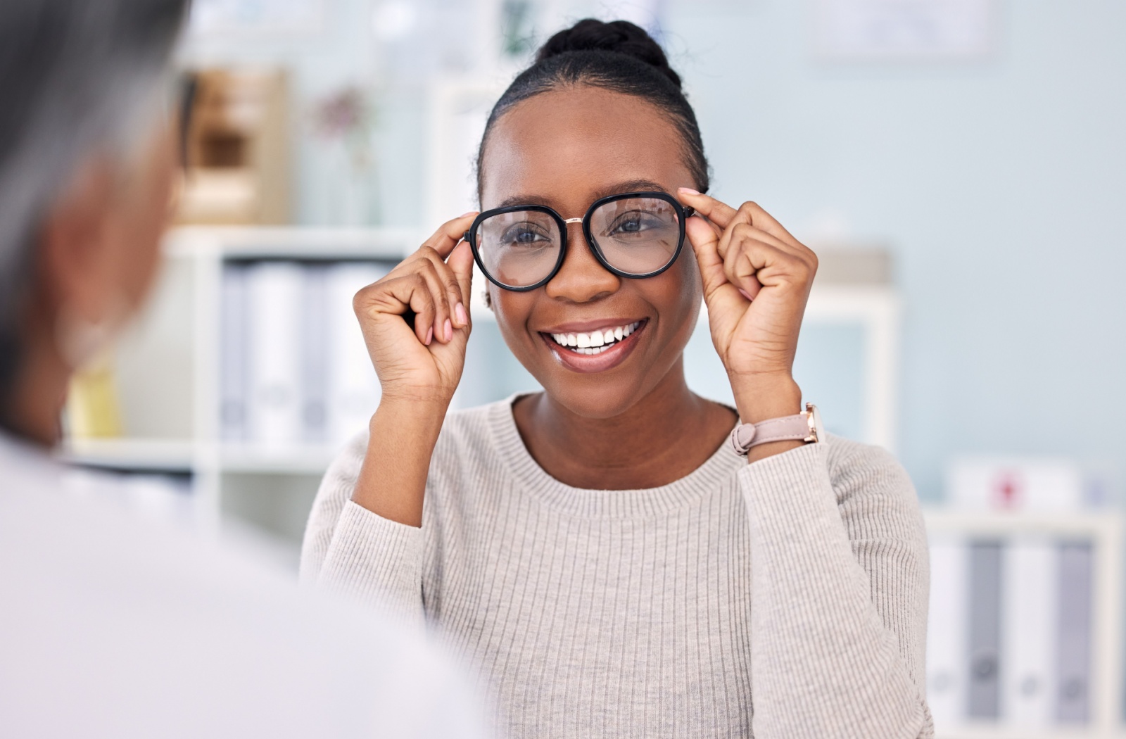 Woman trying on a pair of black rimmed glasses at the optometrist