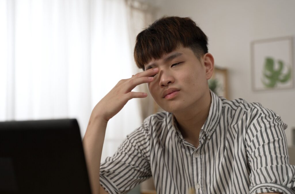 A person rubbing their dry eyes from using the screen too much